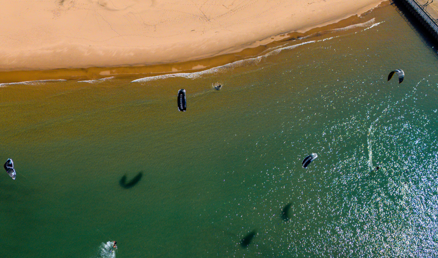 Begginers are having a kitesurfing session in calm waters.